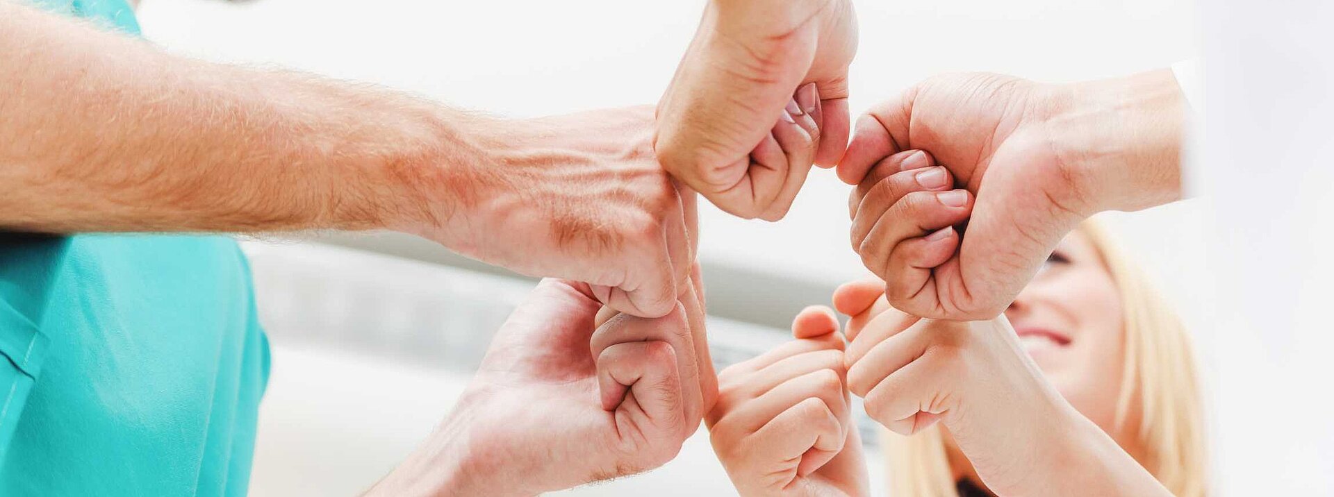Bild von medizinischem Personal, welches eine teambildende Geste macht